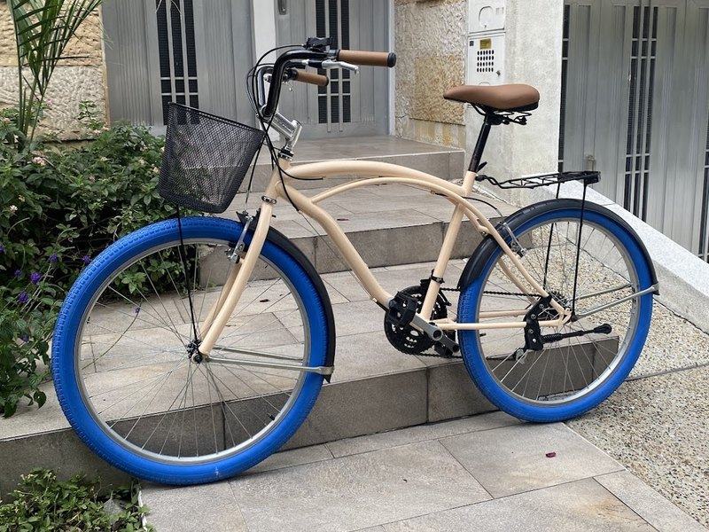 Bicicleta crema con llantas azules y canasta